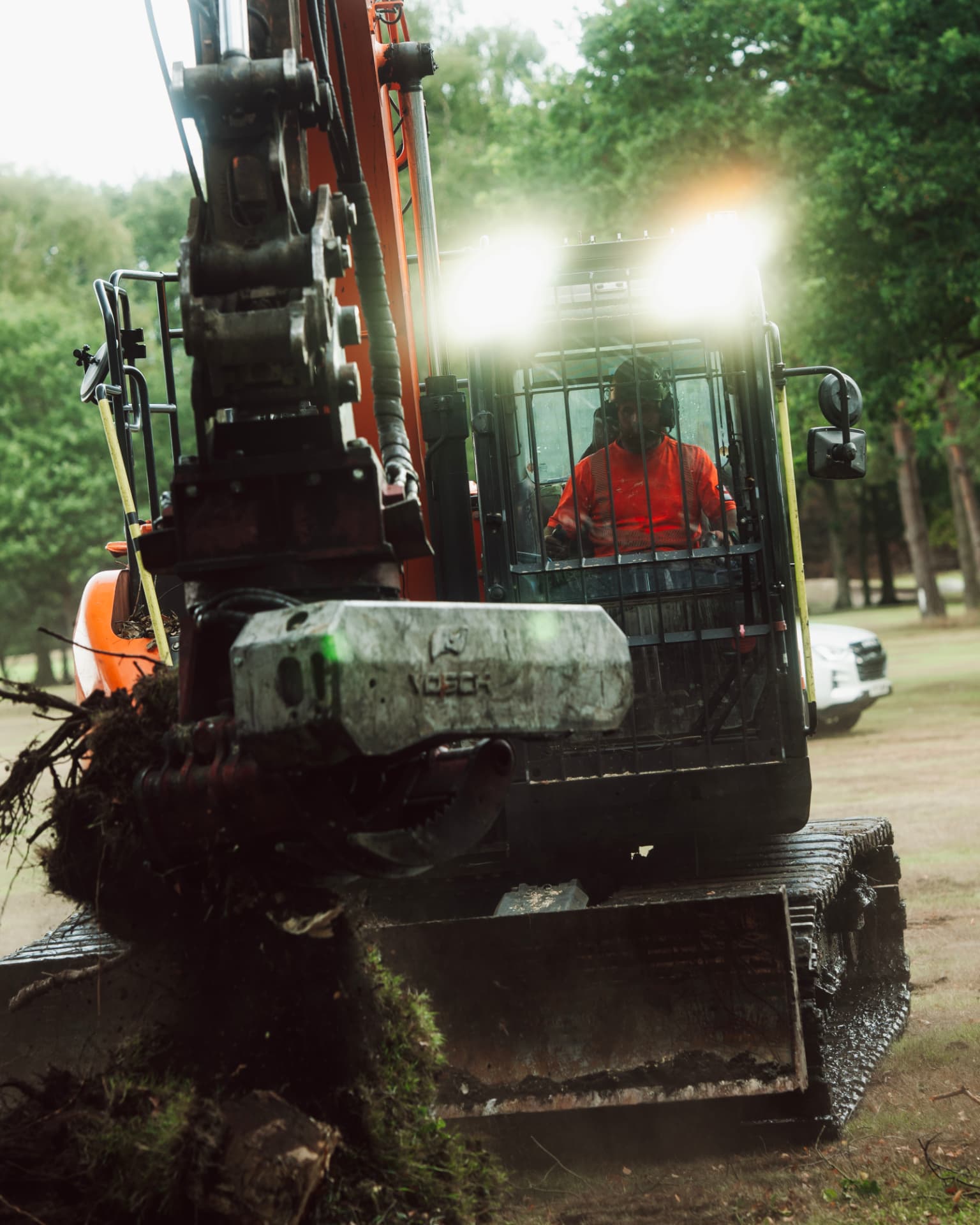Operator in an orange excavator clearing ground